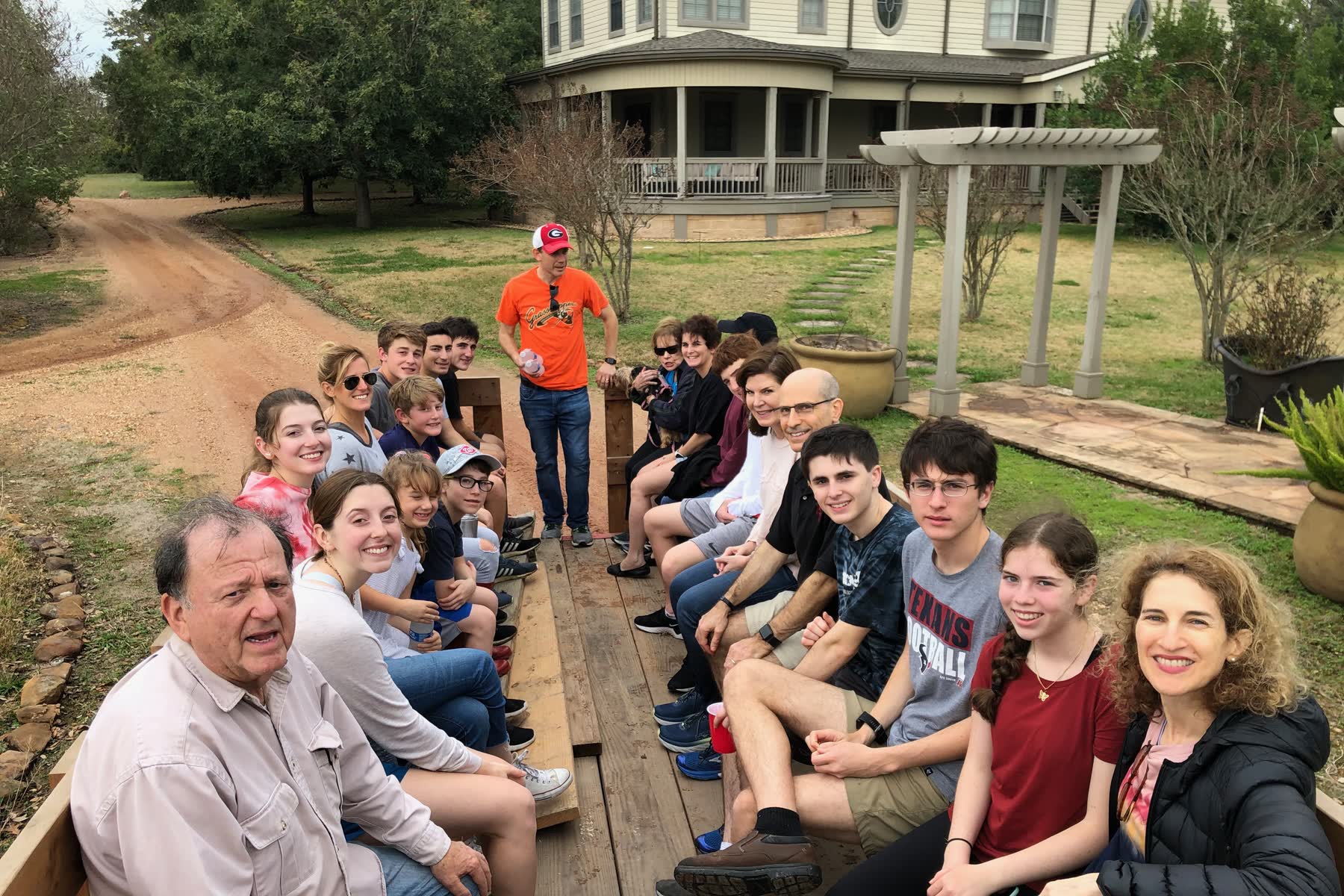 A large family group riding a flatbed wagon up the drive toward the main house at the 5 Star Ranch